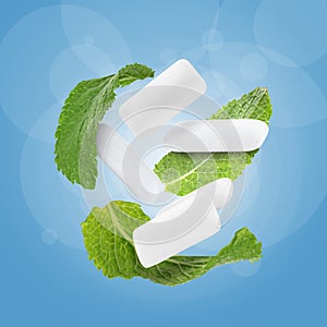 Fresh mint leaves and chewing gum pads falling on blue background