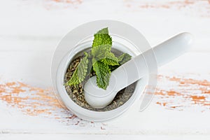 Fresh mint leaves in a mortar on a white wooden table