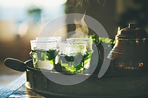 Fresh mint tea in glasses and teapot in tray