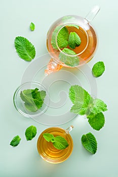 Fresh mint tea in teapot and cup on table. Flat lay, top view