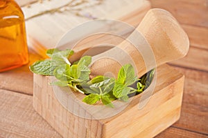 Fresh mint, wooden mortar, pestle,small bootle with mint oil and old book on the old table