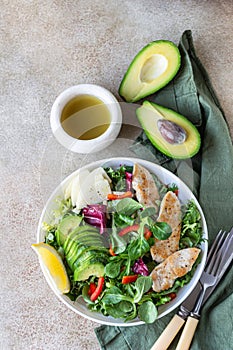Fresh mix salad with grilled chicken fillet, avocado, apple and bell pepper and olive oil and lemon dressing. Healthy food, diet