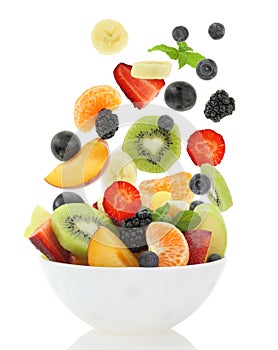 Fresh mixed fruit salad falling into a bowl of salad