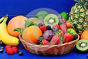 Fresh mixed fruits in a basket on blue table