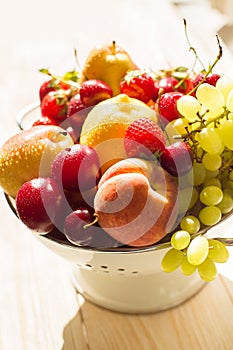 Fresh mixed fruits, berries in colander. Love fruit, berry. Sunlight