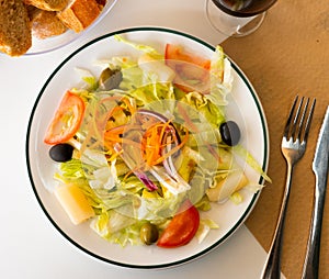 Fresh mixed salad with lettuce, cabbage, carrots, onions, tomatoes, olives. Spanish dish ensalada variada photo