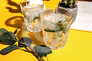 Fresh Mojito alcoholic cocktail with lime, rosemary, mint and ice in jar glass on yellow dots background