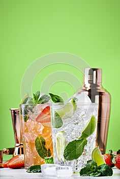 Fresh Mojito cocktail set with lime, mint, strawberry and ice in glass on green background. Summer cold alcoholic non-alcoholic