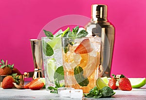Fresh Mojito cocktail set with lime, mint, strawberry and ice in glass on pink background. Summer cold alcoholic non-alcoholic