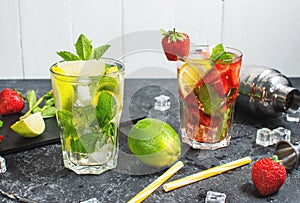 Fresh Mojito cocktail set with lime, mint, strawberry and ice in glass on stone background. Steel bar tools