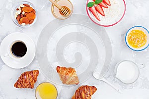 Fresh morning breakfast with coffee, croissant, oatmeal, jam, honey and juice on stone table top view. Flat lay.