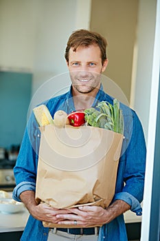 Fresh from Mother natures pantry. Portrait of a happy man holding a bag full of healthy groceries.