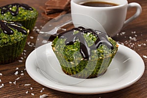 Fresh muffins with spinach, desiccated coconut, chocolate glaze and cup of coffee, delicious healthy dessert