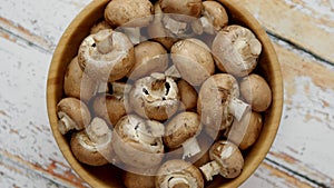 Fresh mushrooms in wooden bowl placed on white wooden table