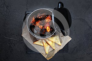 Fresh mussels in a black saucepan in tomato sauce. A traditional seafood boudoir. White bread crackers. Top view. Copy