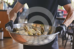 Fresh mussels in copper dish in hands. Waiter with a big bowl of mussels in a restaurant.