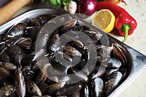 Fresh mussels with ingredients for cooking on rustic background, top view, border. Seafood concept.