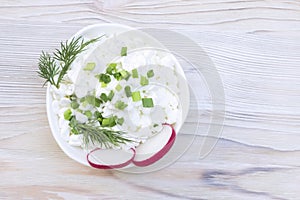 Fresh natural cottage cheese in a white ceramic bowl on the vintage wooden table. Green dill. Organic eco healthy meal, dairy