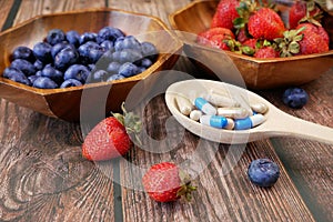 Fresh natural fruits vs pills. Natural vitamin in fruits vs synthetic vitamin in pills. Choice between natural and synthetic way