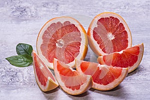 Fresh natural grapefruits with green leaf on a gray wooden table.