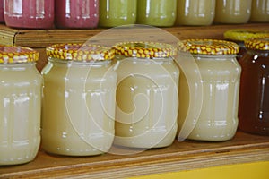 Fresh natural honey in glass jars on wooden shelves in a store