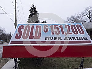 Fresh new sign sold over asking for sale in front of detached house in residential area