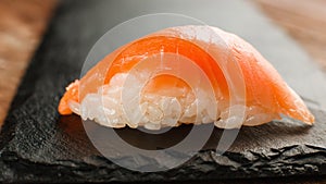 Fresh nigiri salmon sushi on black slate, close up