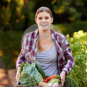 Fresh or nothing. Portrait of a happy young woman holding a crate full of freshly picked vegetables.