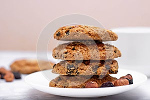 Fresh oatmeal friable cookies on a plate with nuts and raisins. The concept of a delicious and healthy breakfast.