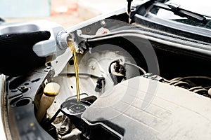 Fresh oil being poured during an oil change to car engine, close photo