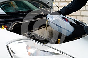 Fresh oil being poured during an oil change to car engine, close