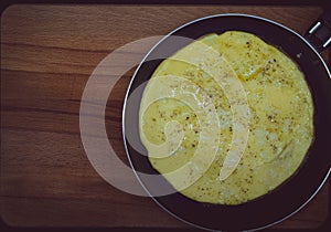 Fresh omelet in the pan. The pan is on a wooden stand. Omelet is made from chicken eggs and milk