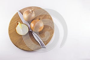 Fresh onion bulbs with knife on cutting board , isolated on whit