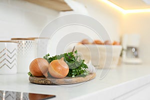 Fresh onions and parsley on white countertop in modern kitchen