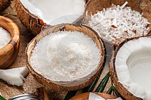Fresh opened coconuts along with coconut slices, flakes and coconut leaves on a wooden table