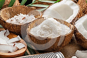 Fresh opened coconuts along with coconut slices, flakes and coconut leaves on a wooden table. photo