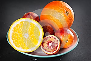 Fresh orange and blood oranges to plate in dark surface