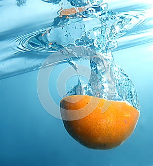 Fresh orange into blue, clear water