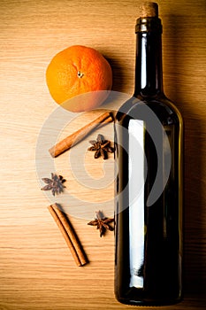 Fresh orange, bottle of vine and spices on a light wooden table.