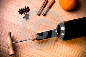 Fresh orange, bottle of vine and spices on a light wooden table.