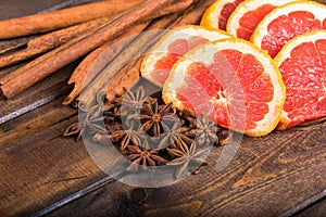 Fresh orange, cinnamon sticks and star anise on dark wood background