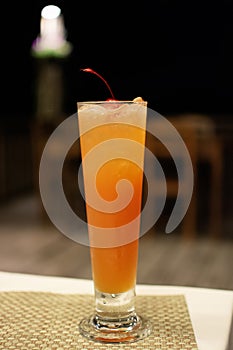 Fresh orange cocktail with ice and cherry standing on the table, alcoholic beverages