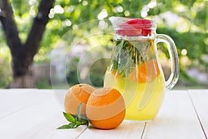 Fresh orange drink in the glass jar. Still life glass jar with orange-mint drink on the wooden table on the natural blurred