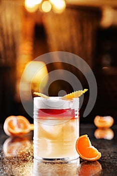 Fresh orange drink with vodka, tangerines and ice in glass on backdrop of the restaurant atmosphere. Summer drinks and cocktails