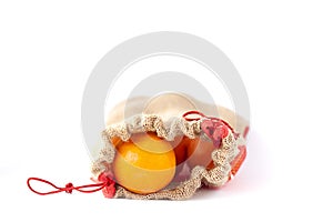 Fresh orange fruits in a burlap bag on white background