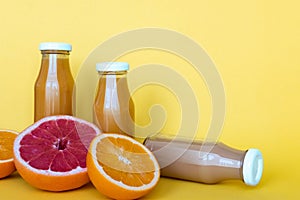 Fresh orange and grapefruit juices with fruits, isolated on yellow background. Place for your text.