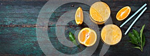 Fresh orange juice with crushed ice and fresh oranges and blue straws on an old vintage exotic background