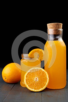 fresh orange juice in a glass jar and bottle with fresh fruits on wooden table