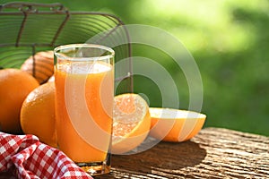 Fresh orange juice in glass with sliced orange on wood and nature background