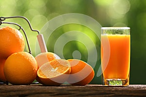 Fresh orange juice in glass with sliced orange on wood and nature background